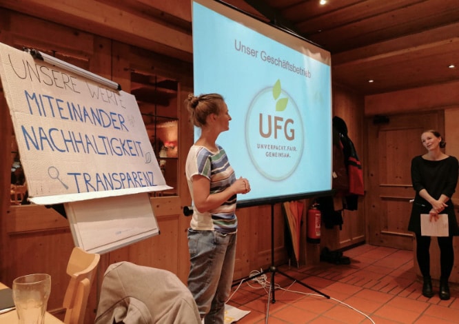 Teaserbild Veranstaltungen – Laura und Wiebke bei einer Veranstaltung vor einer Präsentation auf einer Leinwand