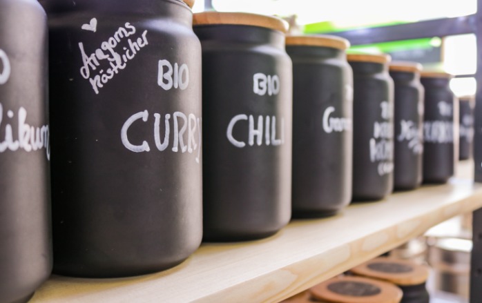 Eine Reihe schwarzer Gewürzbehälter, die allesamt mit weißer Farbe handbeschrieben sind: z.B. Aragorns köstlicher BIO Curry, BIO Chili